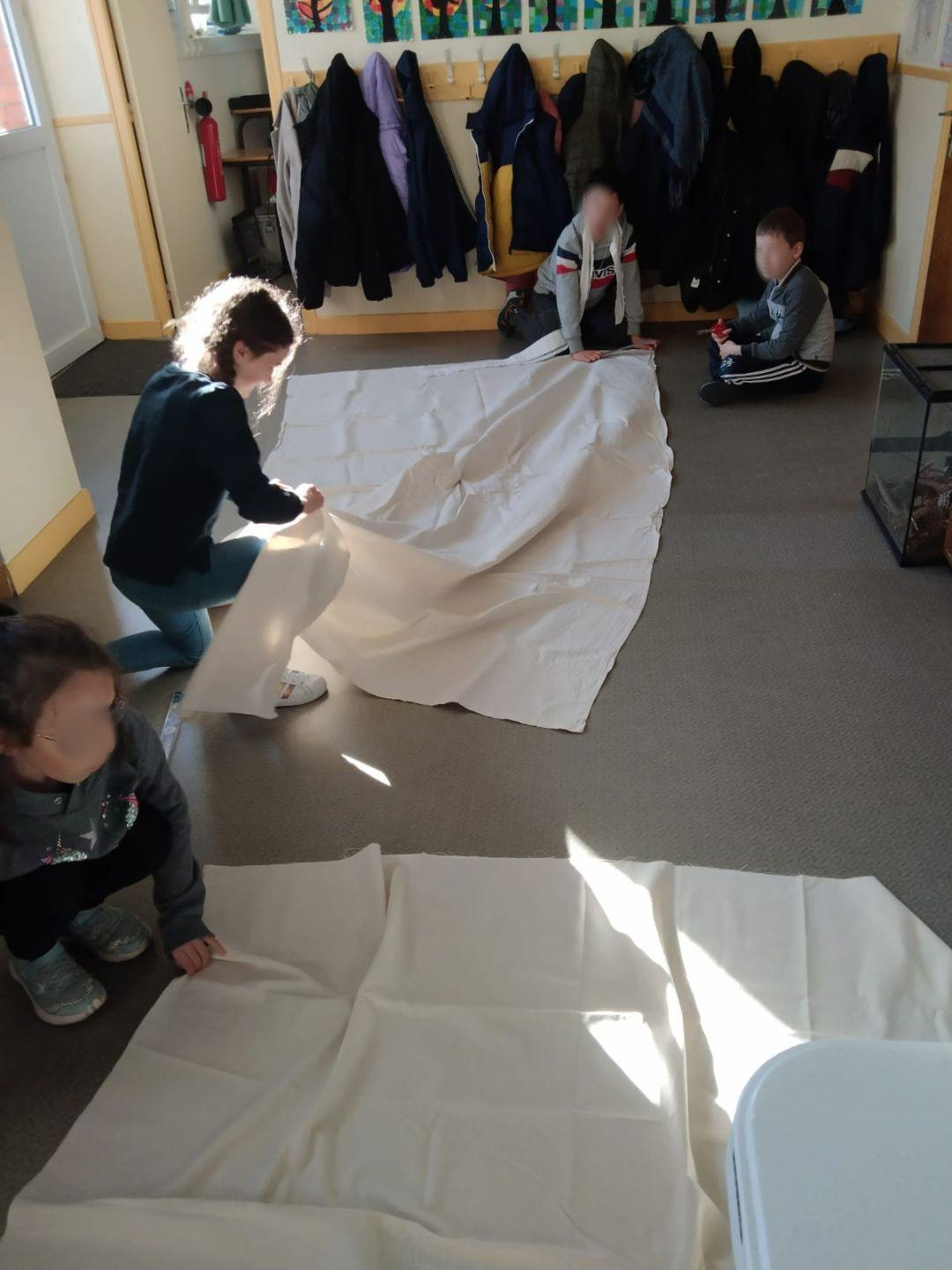 Les élèves récoltent les draps qui serviront à la confection de la voile.